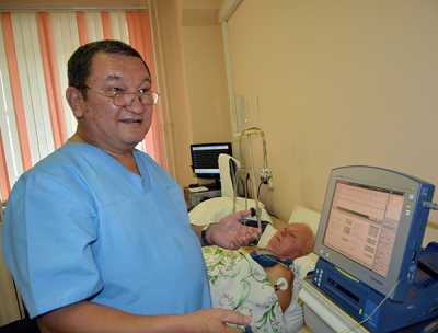 Андрей Чучунов — заслуженный врач РХ, отличник здравоохранения РФ — на программаторе проводит 80-летнему пациенту контрольный опрос имплантируемого устройства. 