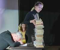 Сцена из спектакля «Несильный». Ассистент воздвигает перед плачущим Кафкой стену из книг, написанных им самим. 