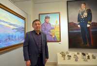 Алексей Ховалыг на фоне своих работ «Туманное утро» и «Портрет Кошкендея Игоря Михайловича». 
