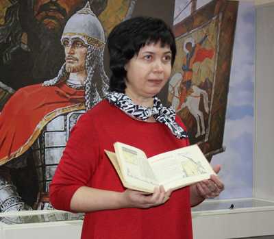Мария Пьянова, заведующая центром чтения и просветительских программ библиотеки, демонстрирует книгу о подвигах Александра Невского, изданную в в годы войны. 